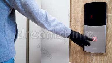 在冠状病毒和传染病流行期间，一个戴着黑色防护手套的人按下电梯按钮。